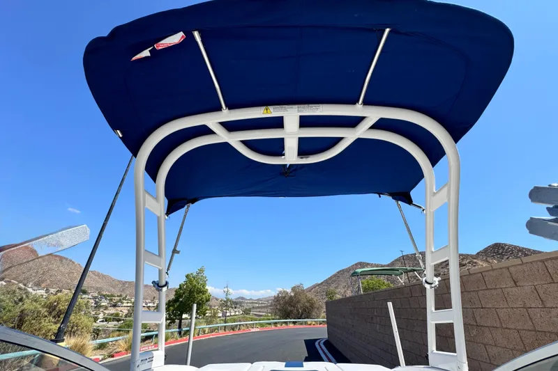 Slide: The Image of 2014 Chaparral 21 H2O Sport boat with blue canopy, scenic mountain backdrop. - 19
