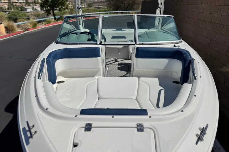 Slide: The Image of 2014 Chaparral 21 H2O Sport boat with white and blue seating, docked outdoors. - 8