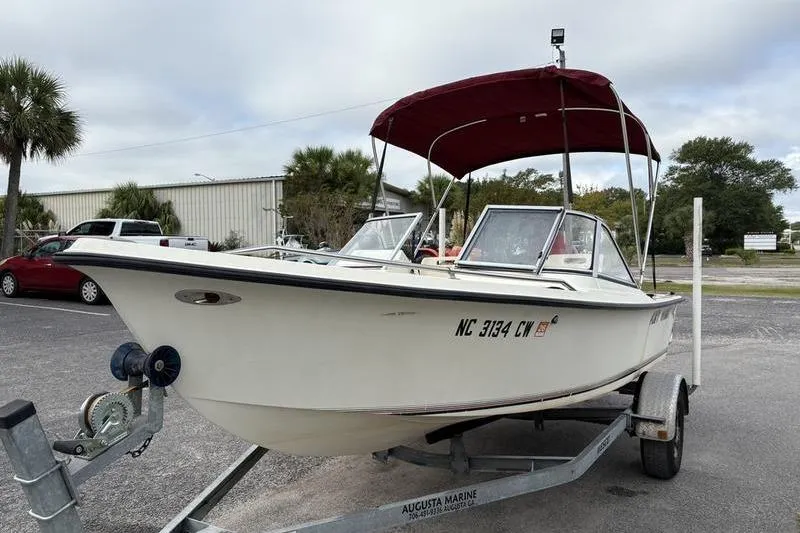 Slide: The Image of 1996 Key West 1720 Dual Console boat on trailer with red canopy in parking lot. - 2