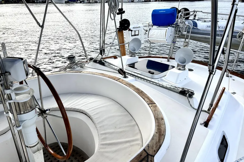 Slide: The Image of Cockpit of 1989 Taswell 43 sailboat with wooden wheel and seating, docked on water. - 13