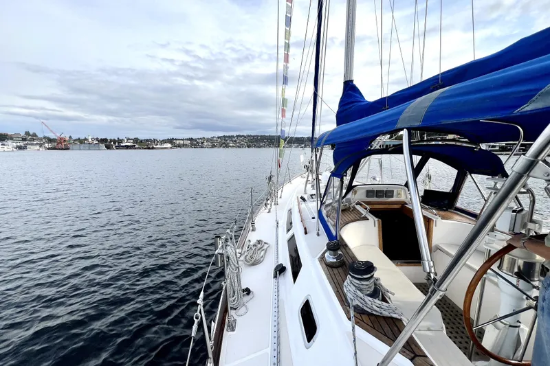 Slide: The Image of 1989 Taswell 43 sailboat with blue canopy on calm waters, scenic coastal view. - 16