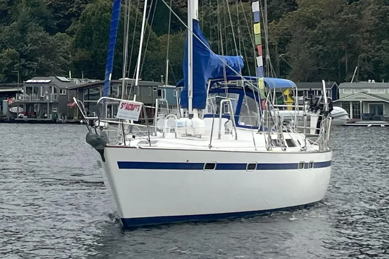 Slide: The Image of 1989 Taswell 43 sailboat on a calm lake with forested shoreline. - 2