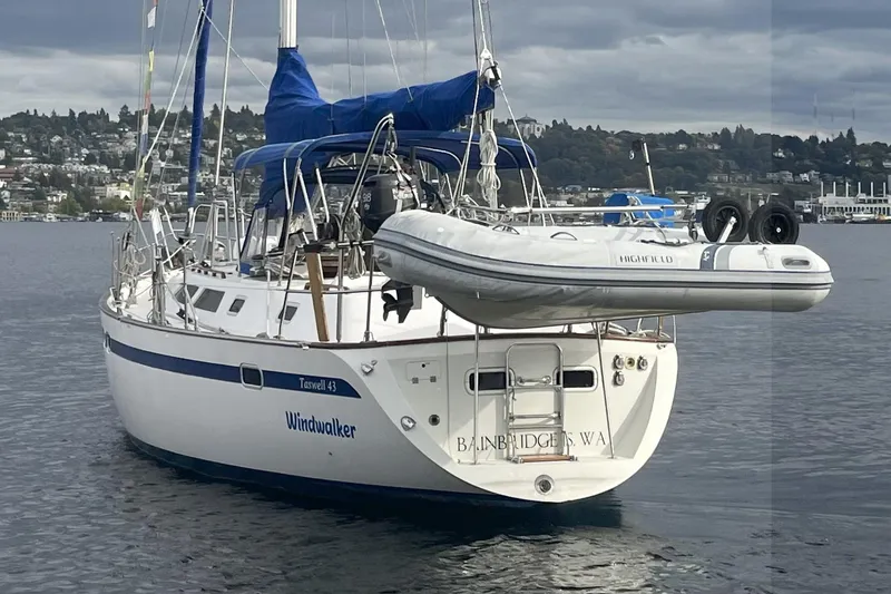 Slide: The Image of 1989 Taswell 43 sailboat named "Windwalker" with dinghy, moored on calm water. - 3
