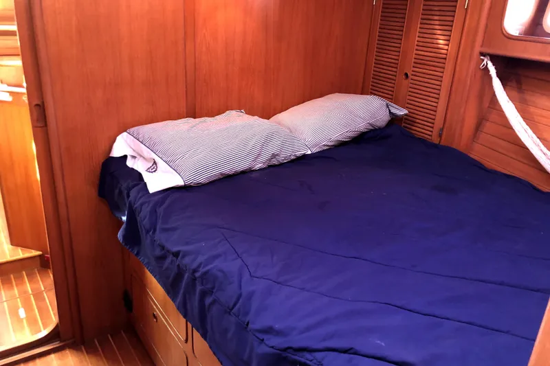 Slide: The Image of Cozy cabin interior of 1989 Taswell 43 sailboat with wooden paneling and blue bedding. - 32