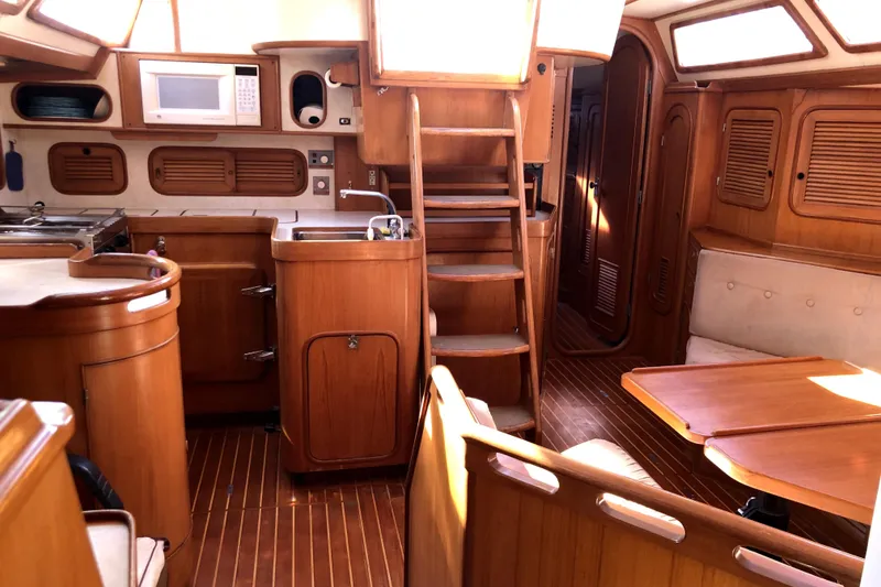 Slide: The Image of 1989 Taswell 43 yacht interior with wooden cabinetry, dining area, and kitchen amenities. - 34