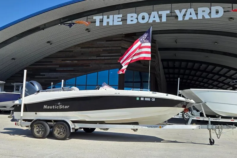 Slide: The Image of 2021 NauticStar 203 SE boat on trailer in outdoor dealership lot. - 2