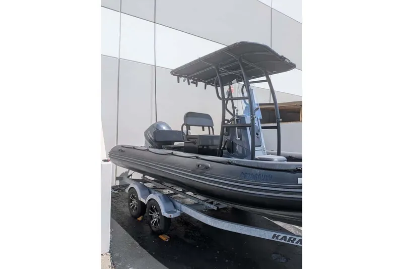 Slide: The Image of 2022 Zodiac 20 boat on trailer, parked near a modern building. - 16