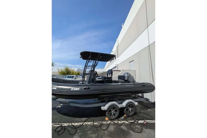 Slide: The Image of 2022 Zodiac 20 boat on trailer, parked near a building under clear blue sky. - 3