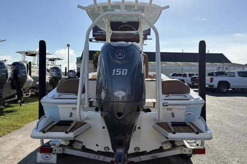 Slide: The Image of 2025 Pioneer 202 Islander boat with Yamaha 150 outboard motor, parked outdoors. - 2