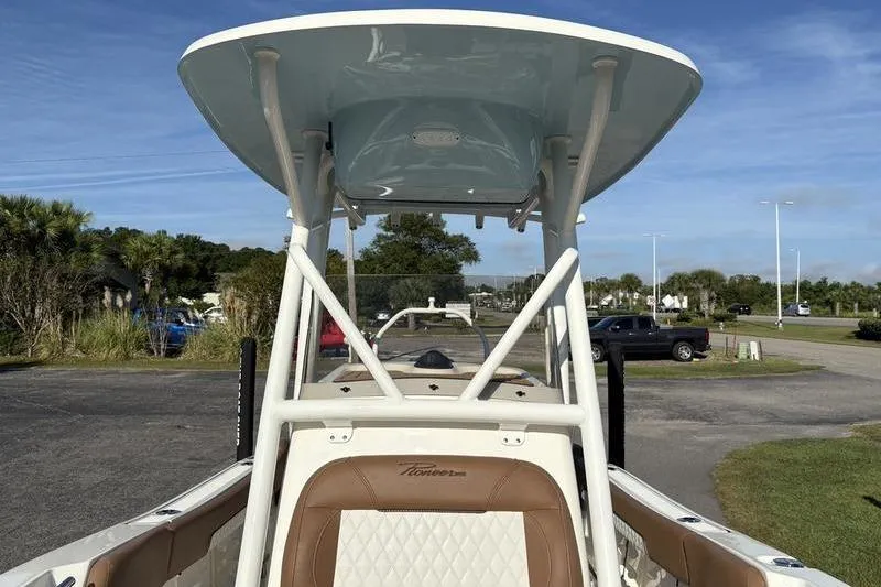 Slide: The Image of 2025 Pioneer 202 Islander boat with T-top and seating, parked outdoors. - 25