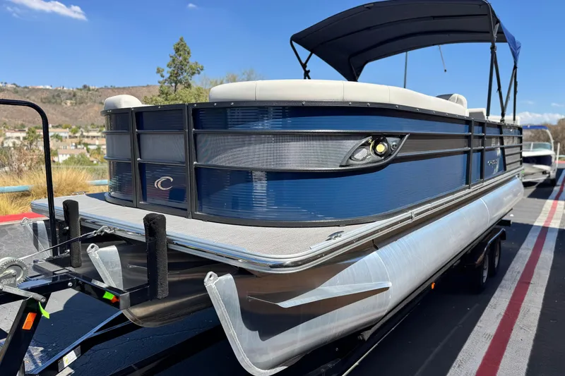 Slide: The Image of 2022 Crest Classic DLX 240 SLRC pontoon boat on trailer, blue exterior, sunny day. - 3
