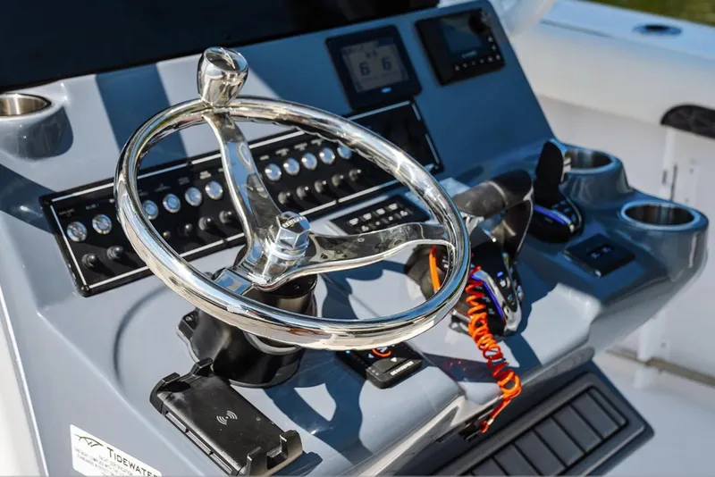 Slide: The Image of 2026 Tidewater 282 CC Adventure boat interior with seating and console, under clear blue sky. - 6