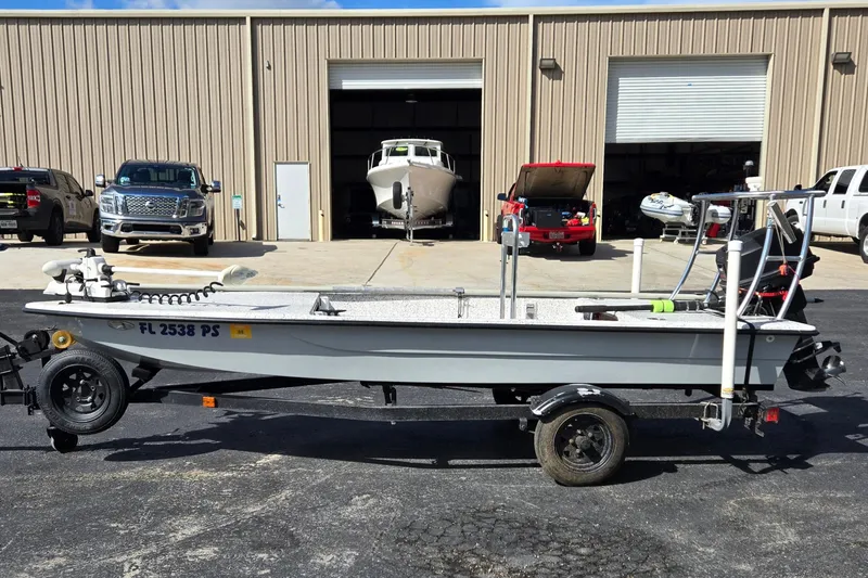 Slide: The Image of 2014 IBP 14 Skiff boat on trailer, parked outside a garage with vehicles. - 6