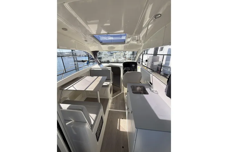 Slide: The Image of 2023 Bayliner Trophy T25 Explorer cabin interior with gray bedding and curtain. - 8