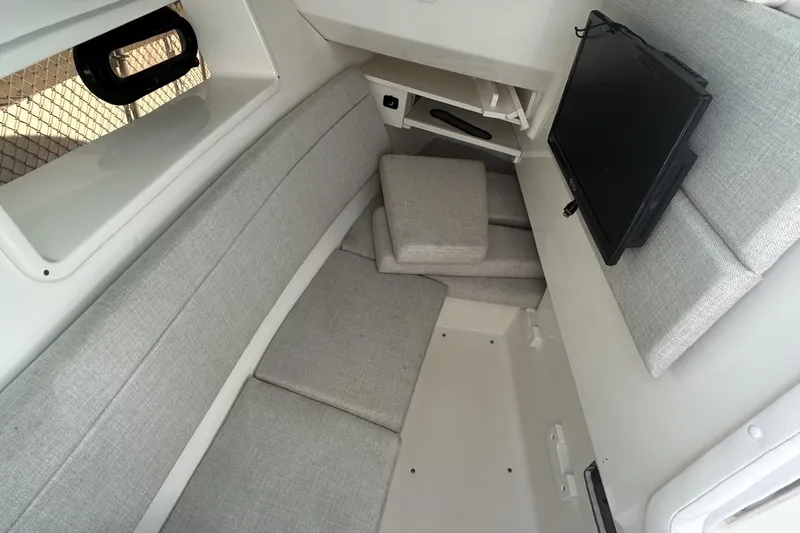 Slide: The Image of 2019 Sea Ray SLX 350 Outboard cabin interior with gray seating and mounted TV. - 27