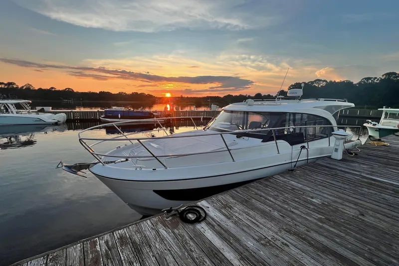 The Image of 2024 Beneteau Antares 11 docked at sunset, reflecting on calm water. - 0