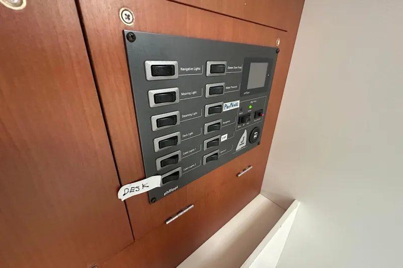 Slide: The Image of Electrical control panel on 2021 J Boats J99 yacht, featuring labeled switches and wooden finish. - 25
