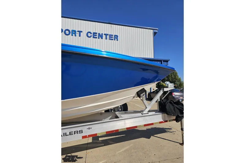 Slide: The Image of 2002 Hustler 388 SLINGSHOT boat on trailer at a port center. - 14