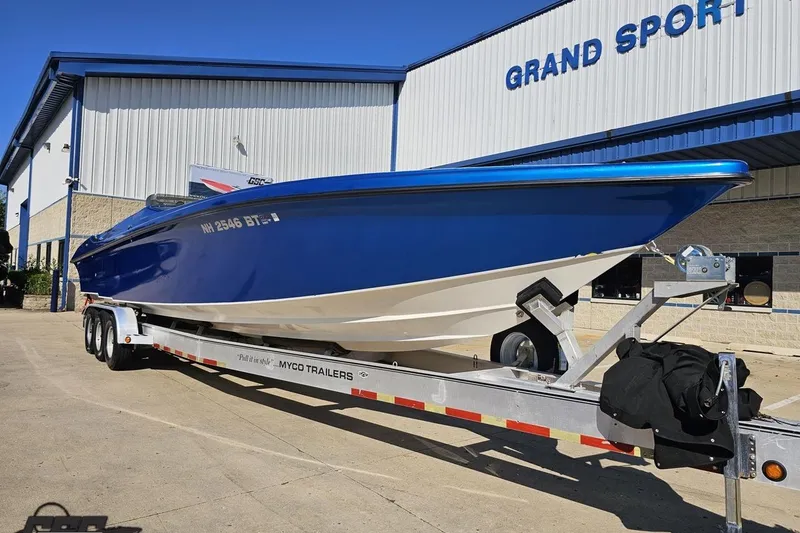 Slide: The Image of 2002 Hustler 388 SLINGSHOT boat on trailer outside Grand Sport building. - 15