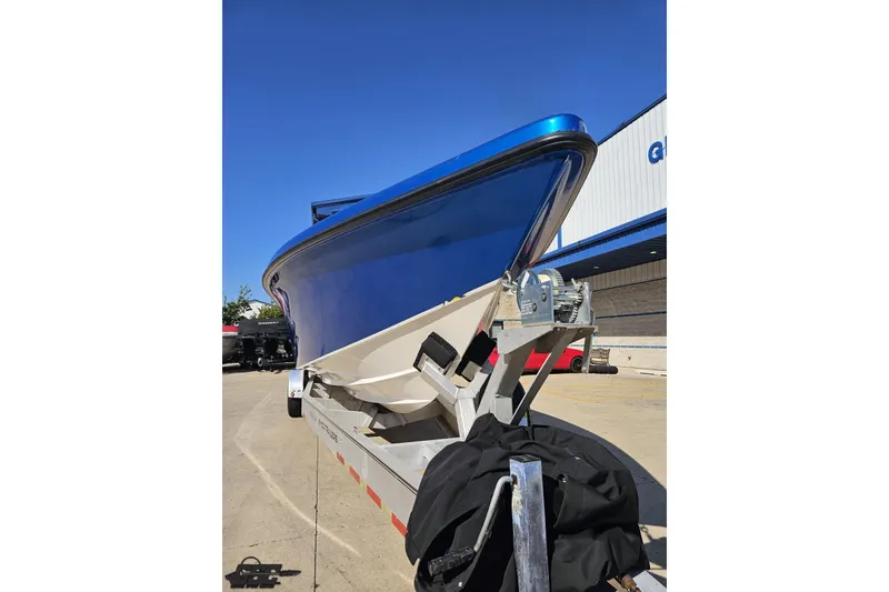 Slide: The Image of 2002 Hustler 388 SLINGSHOT boat on trailer, blue hull, parked outdoors. - 16