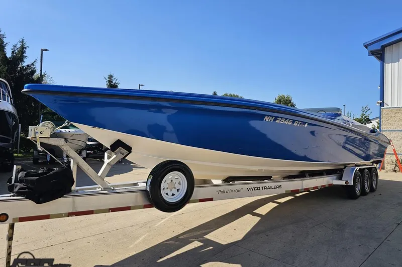 Slide: The Image of 2002 Hustler 388 SLINGSHOT speedboat on trailer, blue and white design, parked outdoors. - 19
