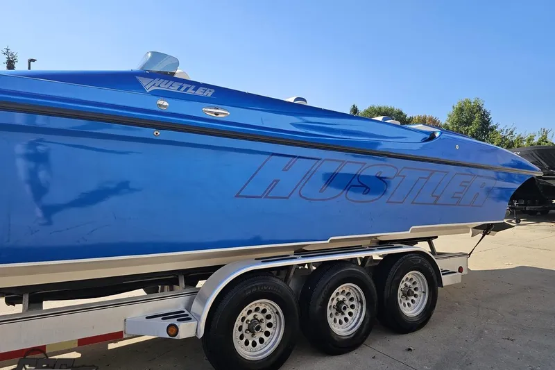 Slide: The Image of 2002 Hustler 388 SLINGSHOT boat in vibrant blue on a trailer. - 26