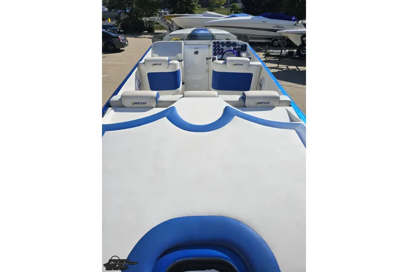 Slide: The Image of 2002 Hustler 388 SLINGSHOT boat interior with blue and white seating, parked outdoors. - 46