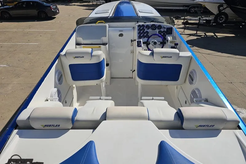 Slide: The Image of 2002 Hustler 388 SLINGSHOT boat interior with blue and white seating and control panel. - 49