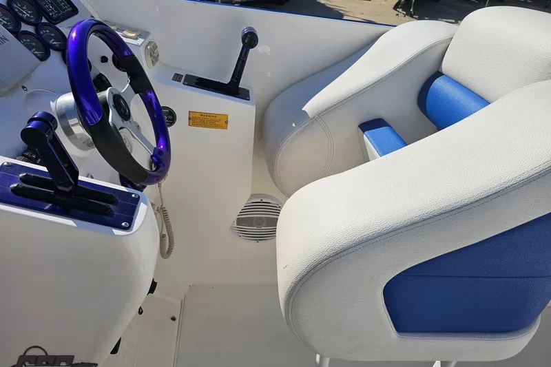 Slide: The Image of Interior of 2002 Hustler 388 SLINGSHOT boat with blue and white seating and controls. - 55