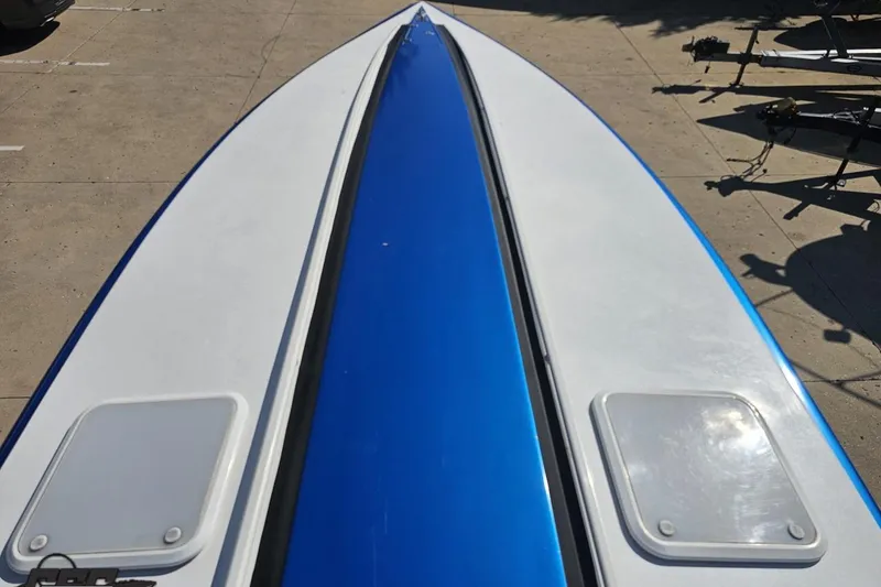 Slide: The Image of 2002 Hustler 388 SLINGSHOT boat deck with blue and white design in a parking area. - 62