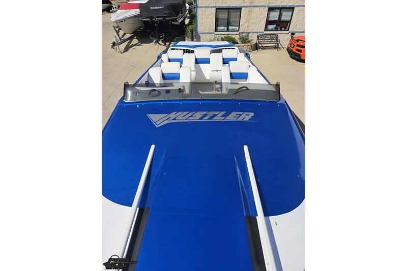 Slide: The Image of 2002 Hustler 388 SLINGSHOT speedboat with blue and white design, docked outdoors. - 63