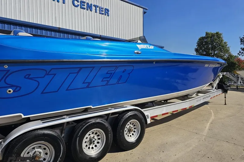Slide: The Image of Blue 2002 Hustler 388 SLINGSHOT boat on trailer outside a service center. - 8