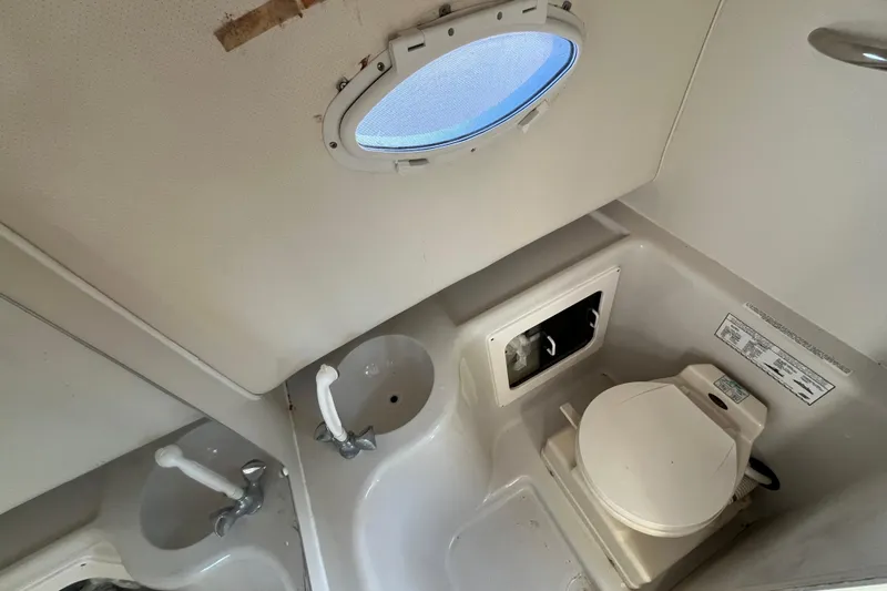 Slide: The Image of 1994 Pro-Line 2950 boat bathroom with toilet, sink, and porthole window. - 11