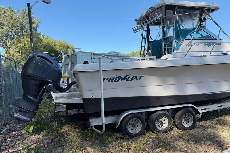 Slide: The Image of 1994 Pro-Line 2950 boat on trailer with outboard motor, parked outdoors. - 3