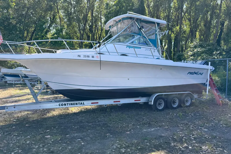 Slide: The Image of 1994 Pro-Line 2950 boat on trailer, surrounded by trees, parked outdoors. - 6