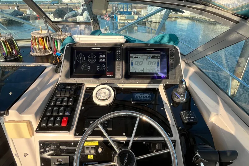 Slide: The Image of 1994 Pro-Line 2950 boat dashboard with navigation screens and steering wheel, docked at marina. - 7