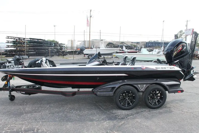 Slide: The Image of 2026 Skeeter FXR20 FLEX bass boat on trailer, side view in a marina setting. - 9