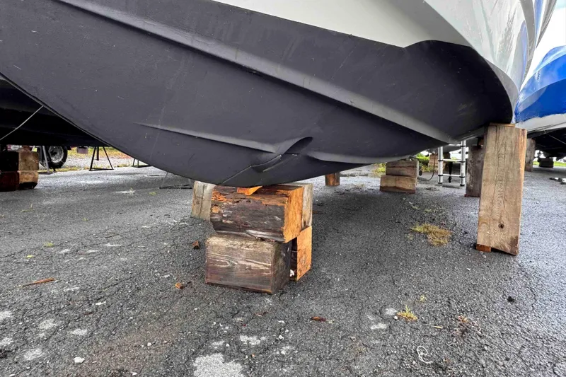 Slide: The Image of 2019 Monterey 295 Sport Yacht hull supported by wooden blocks on asphalt. - 15