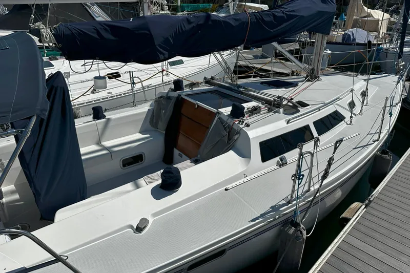 The Image of 1995 Catalina 320 sailboat docked, featuring a sleek white deck and covered sails. - 0