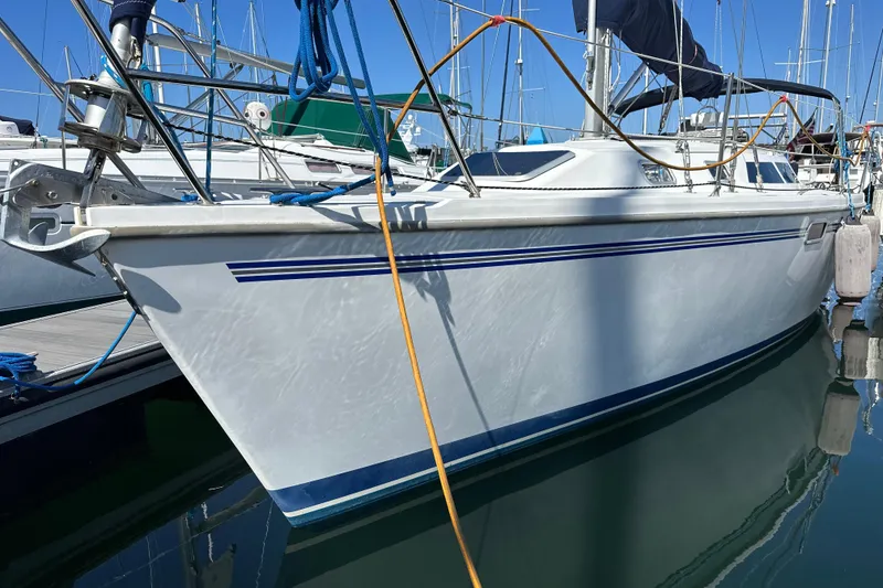 Slide: The Image of 1995 Catalina 320 sailboat docked in marina, featuring sleek white hull and blue accents. - 1