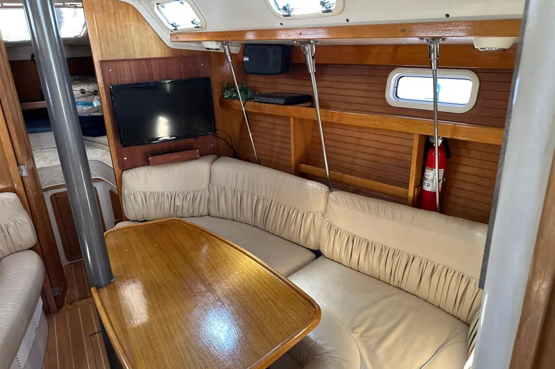 Slide: The Image of Cozy interior of 1995 Catalina 320 sailboat with seating, table, and TV. - 10