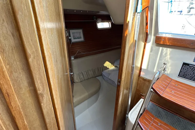Slide: The Image of Interior of a 1995 Catalina 320 sailboat, featuring wooden finishes and cozy seating. - 16