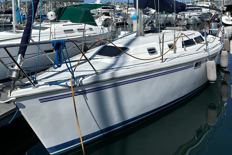Slide: The Image of 1995 Catalina 320 sailboat docked in marina, featuring sleek white hull and blue accents. - 22