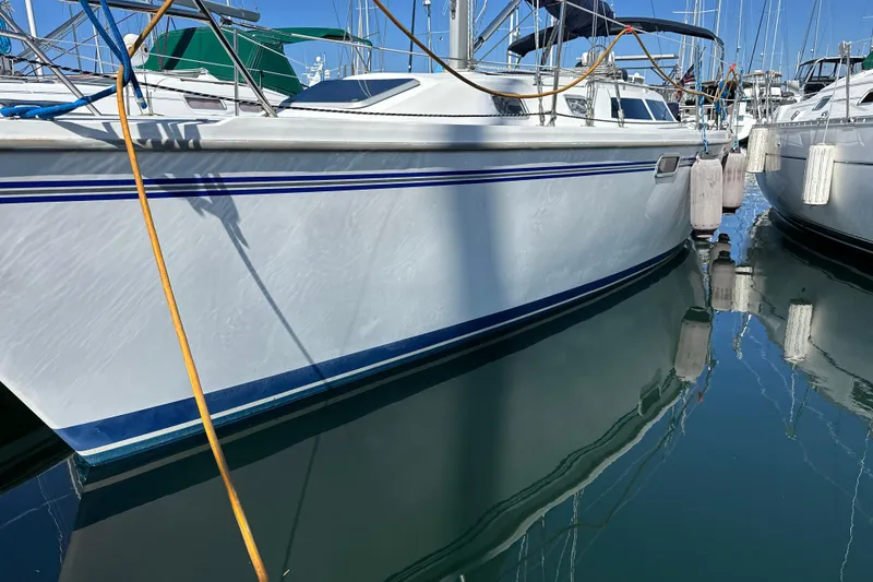 Slide: The Image of Sailboat Catalina 320, 1995 model, docked in marina with calm water reflection. - 23