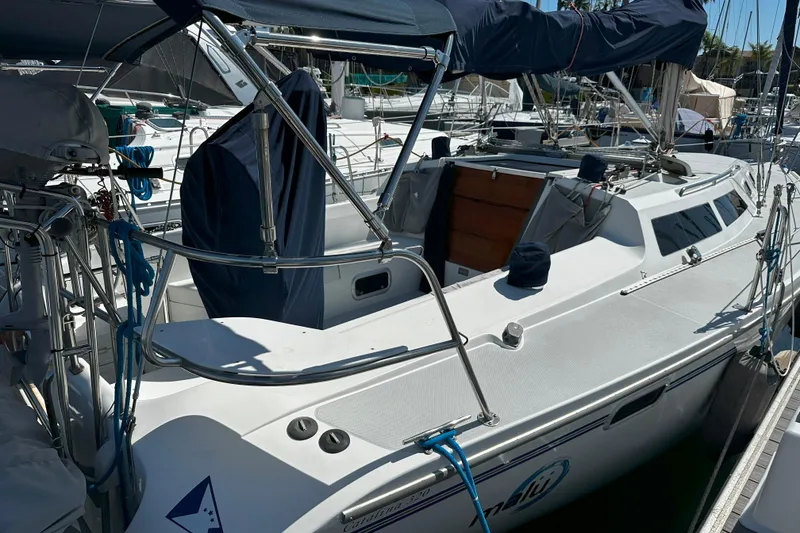 Slide: The Image of 1995 Catalina 320 sailboat docked, featuring a spacious cockpit and covered seating area. - 33