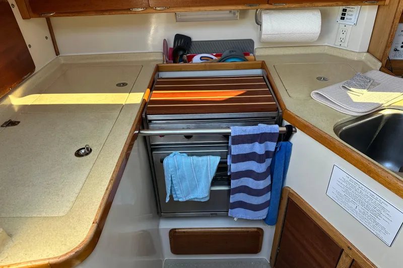 Slide: The Image of Compact kitchen area in a 1995 Catalina 320 sailboat with stove and sink. - 8