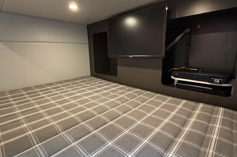 Slide: The Image of 2020 Formula 350 Crossover Bowrider cabin with plaid bedding and mounted TV. - 51