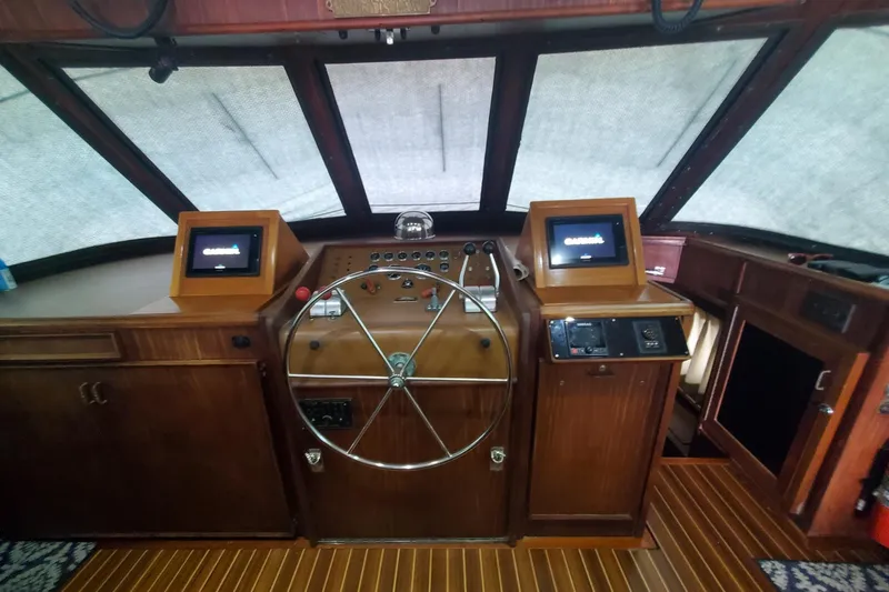 Slide: The Image of 1981 Hatteras 56 Motor Yacht helm with wooden dashboard and modern navigation screens. - 10