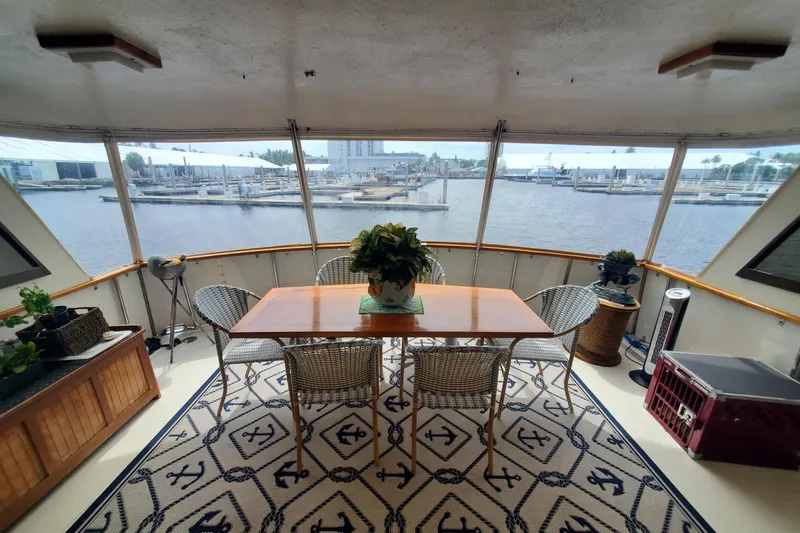 Slide: The Image of 1981 Hatteras 56 Motor Yacht interior with dining area, wicker chairs, and marina view. - 14