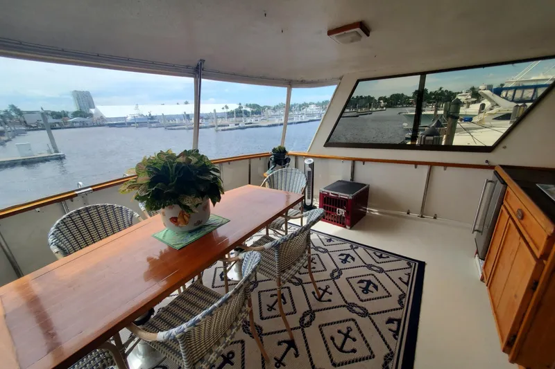 Slide: The Image of 1981 Hatteras 56 Motor Yacht aft deck with dining table, chairs, and marina view. - 16